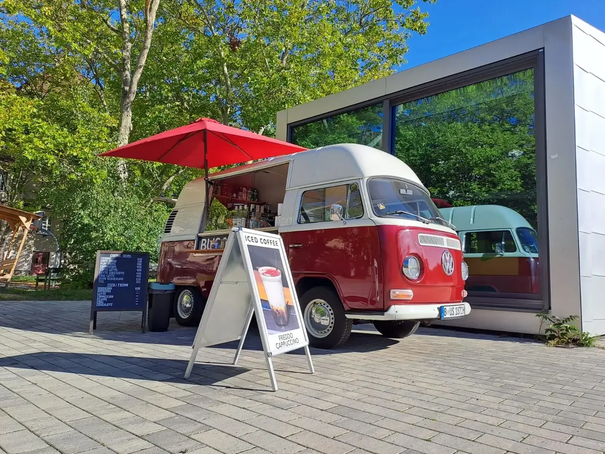 Der Bulli mit Sonnenschirm und Aufsteller im Sommer