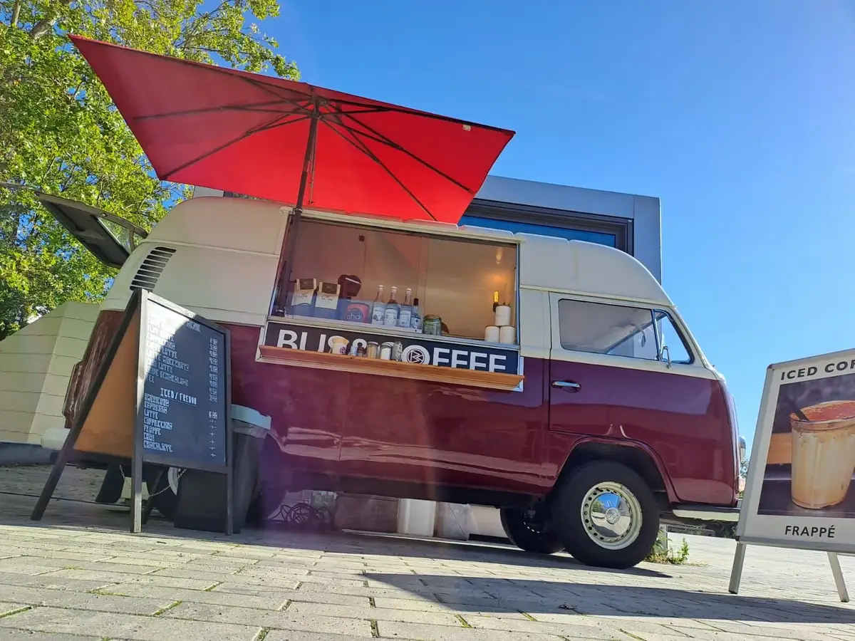 Der Bulli mit rotem Sonnenschirm bei einem Outdoor-Event